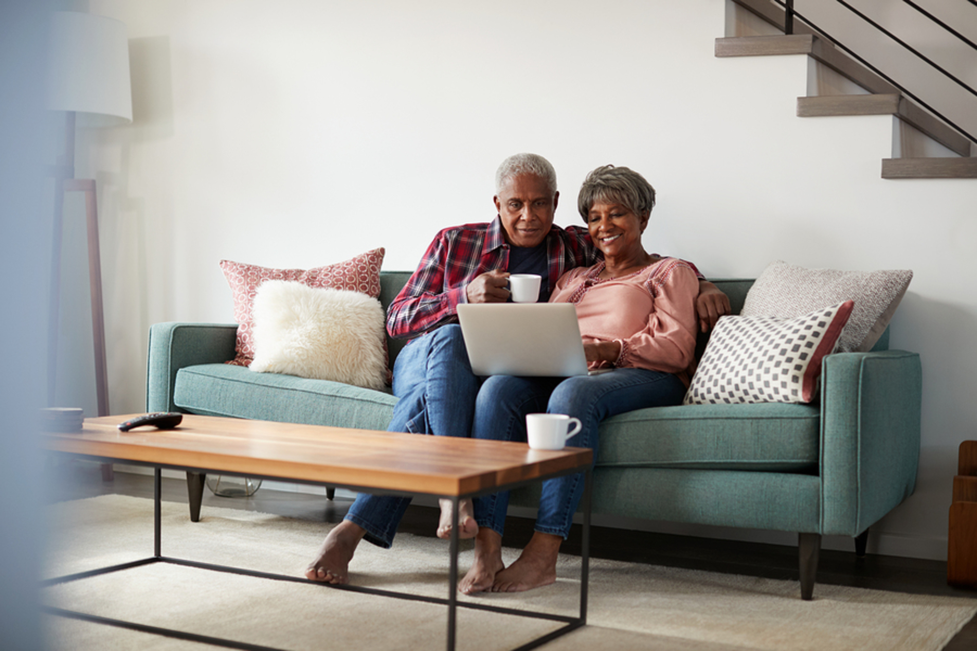 Older couple sitting on a couch looking at a laptop.